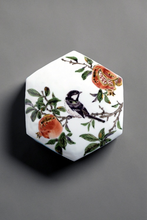 Ceramic by Keiko Mori titled Hexagonal Box with Chickadee and Pomegranate (ca. 2001). Top of box lid with bird on a branch with fruit on a white background.