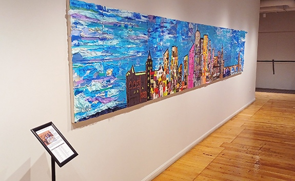 Collaborative collage mural by sixteen art educators and Alice Mizrachi titled Minneapolis Skyline (2024). Cityscape of the Minneapolis skyline with colorful buildings and blue sky.