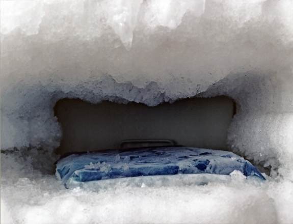 Photograph by Orit Raff titled Untitled (Freezer #6) (2000). Iced over freezer interior with blue ice pack inside.