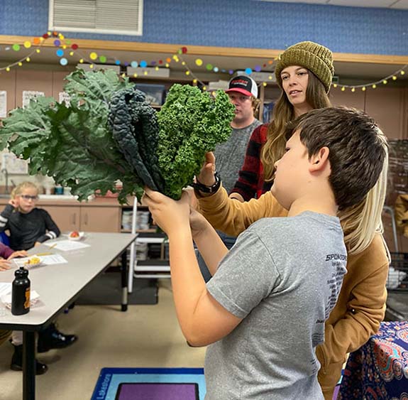 Bill, grade four, holds kale from local farmer Nichole (pictured).